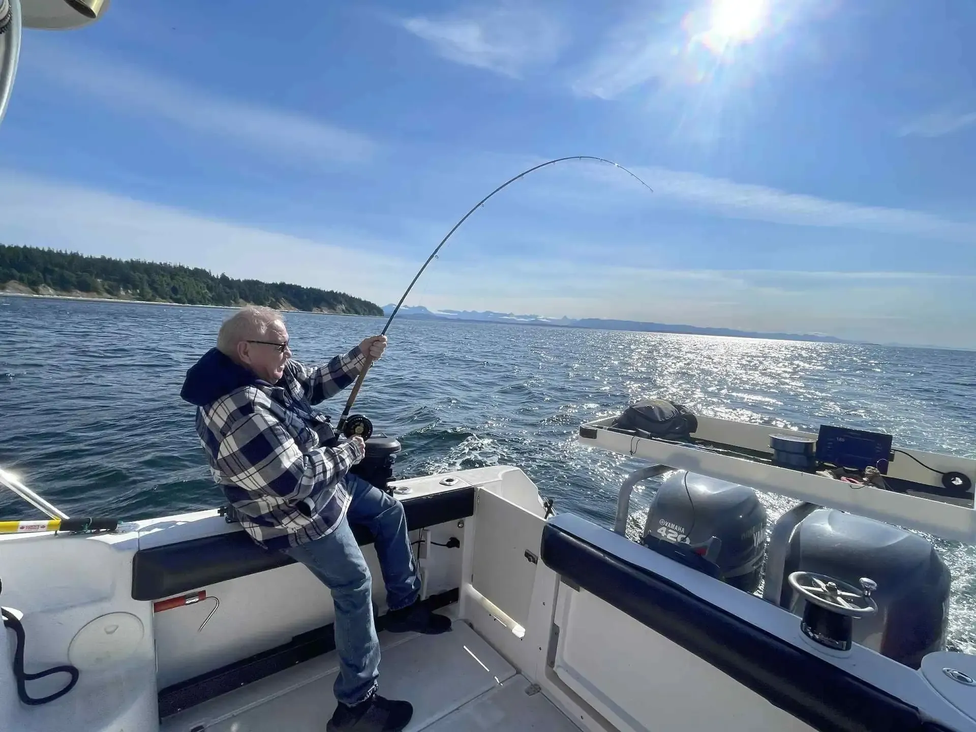 Salmon fishing action - angler fighting fish with bent rod Campbell River