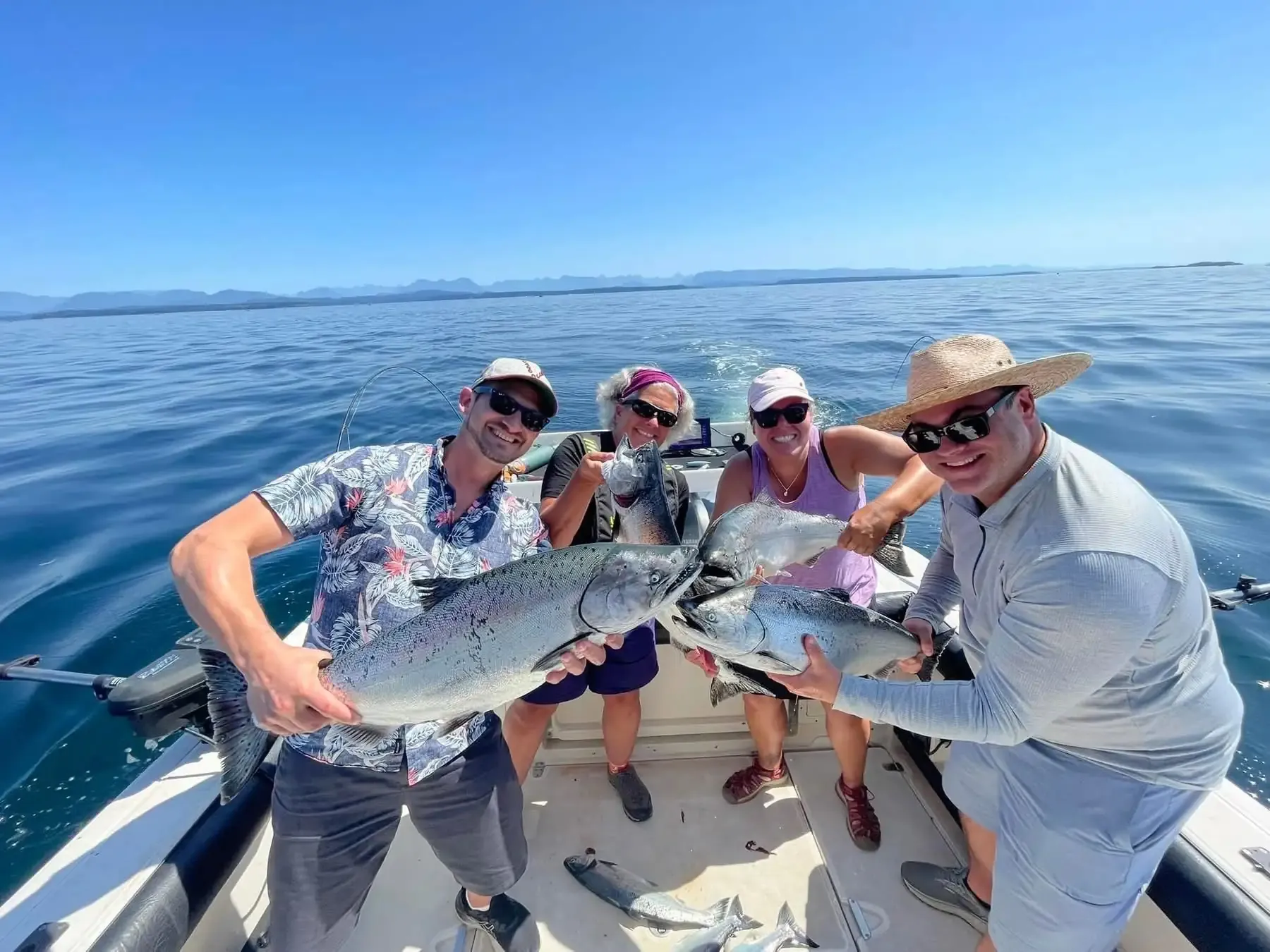 Friends celebrating salmon catches on group fishing charter Campbell River